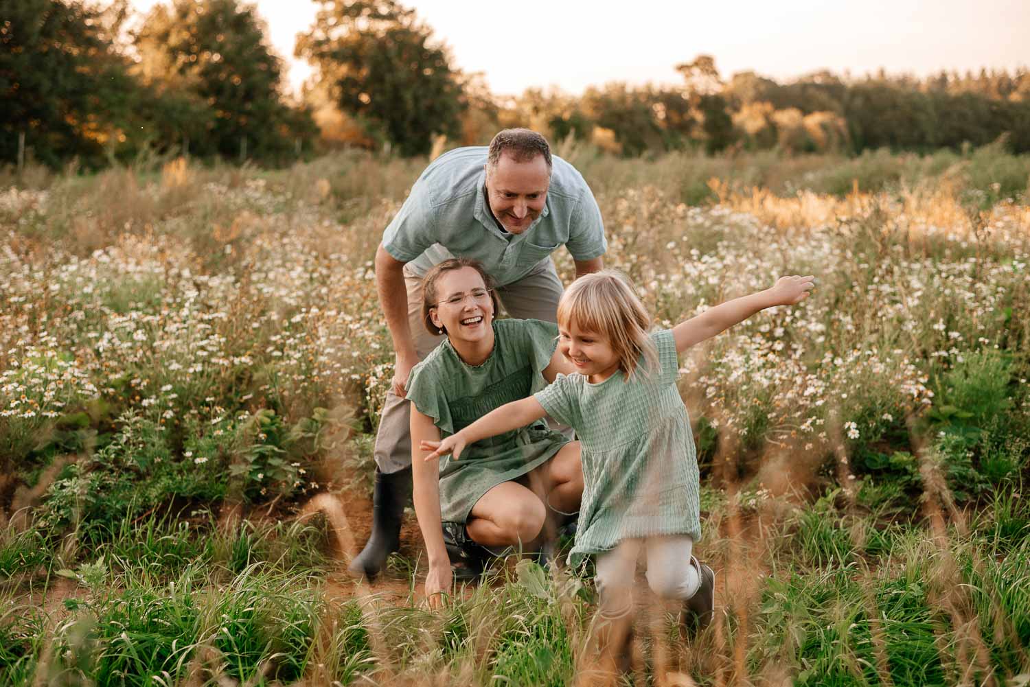 Familie spielt im Blumenfeld. Die Tochter macht den Flugzeug.