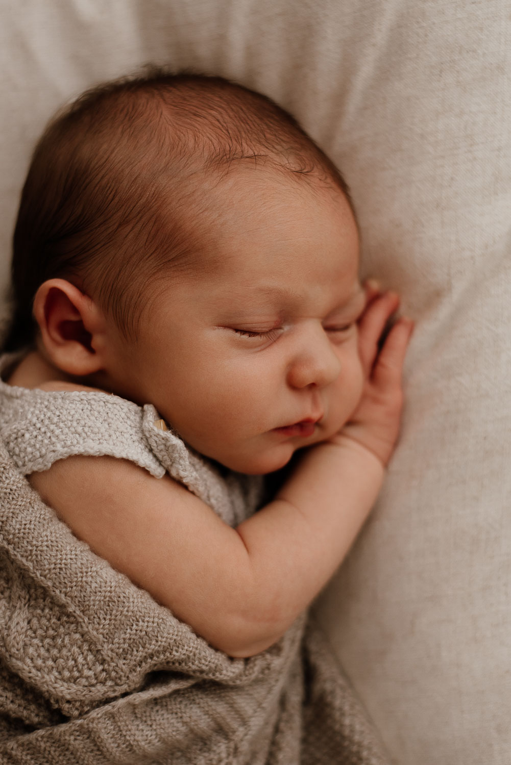 Neugeborenes Baby schläft mit seiner Hand unter der Wange.