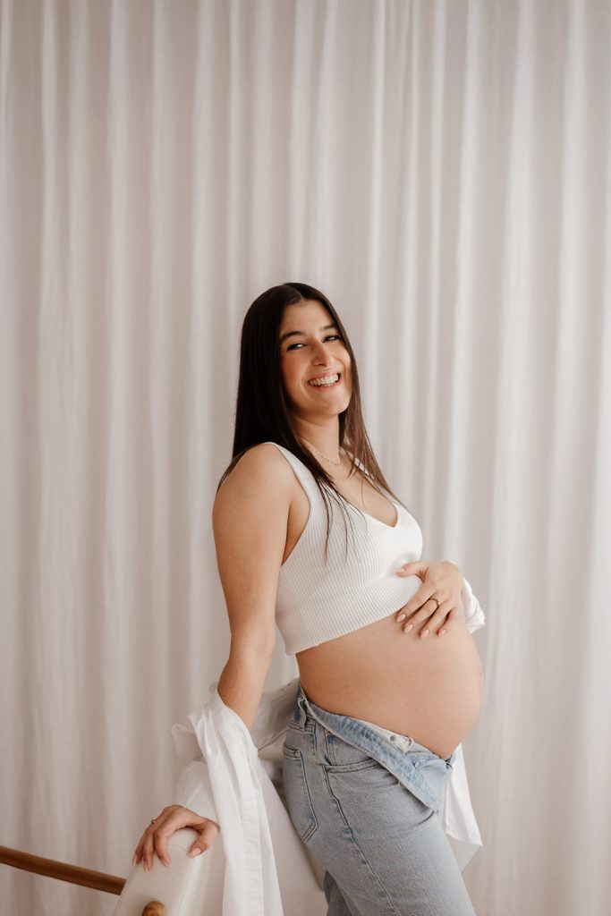 Babybauchshooting in der Nähe von Neumünster im gemütlichen Studio mit Hemd und Jeans für ein zeitloses und klassisches Look.