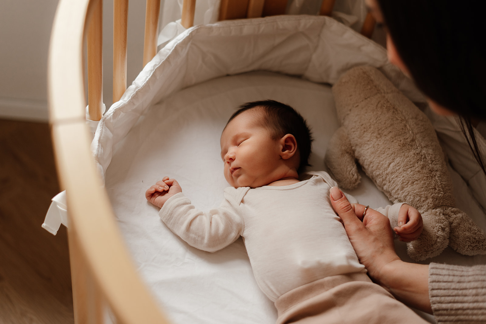 Neugeborenes Baby schläft friedlich im Beistellbett während einer natürlichen Neugeborenenreportage voller Geborgenheit und Ruhe in Kiel.