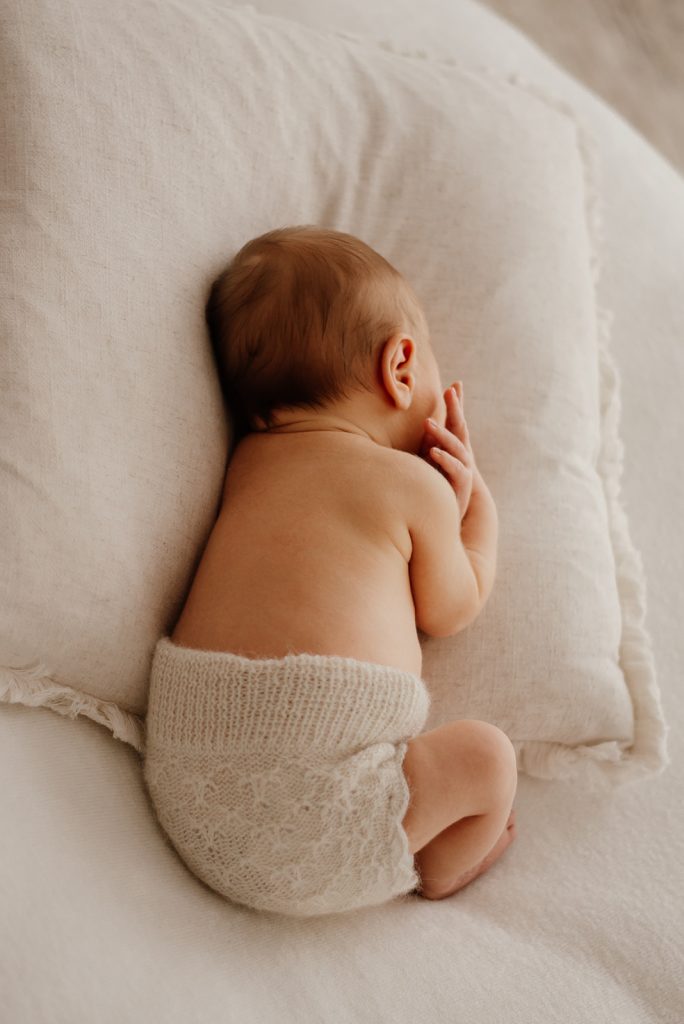 Neugeborenes Baby liegt ruhig und geborgen mit dem Rücken zur Kamera bei einem natürlichen Newborn-Fotoshooting in der Nähe von Kiel.